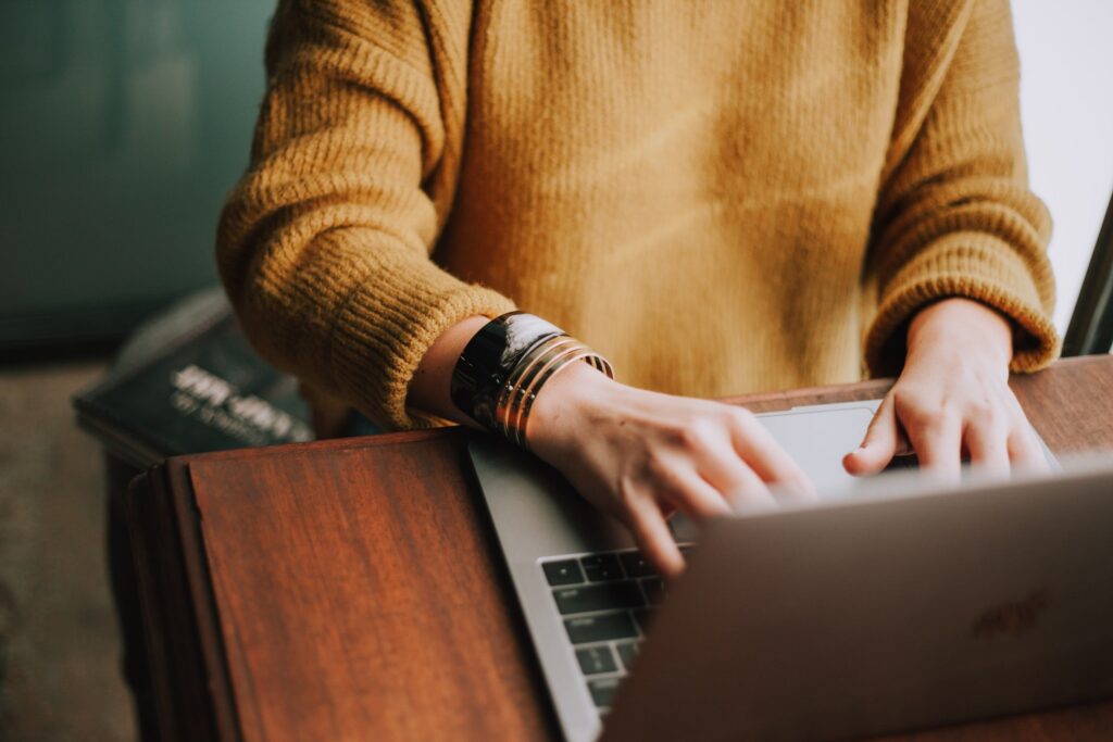 person in a yellow sweater on the computer