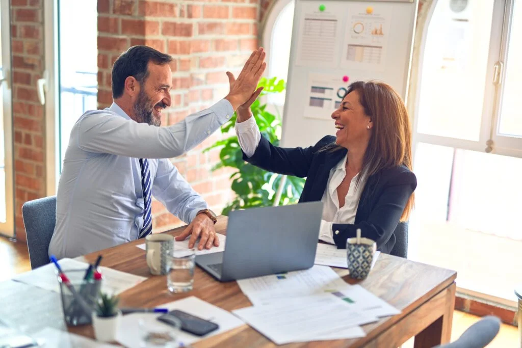 professionals performing a high five over a laptop