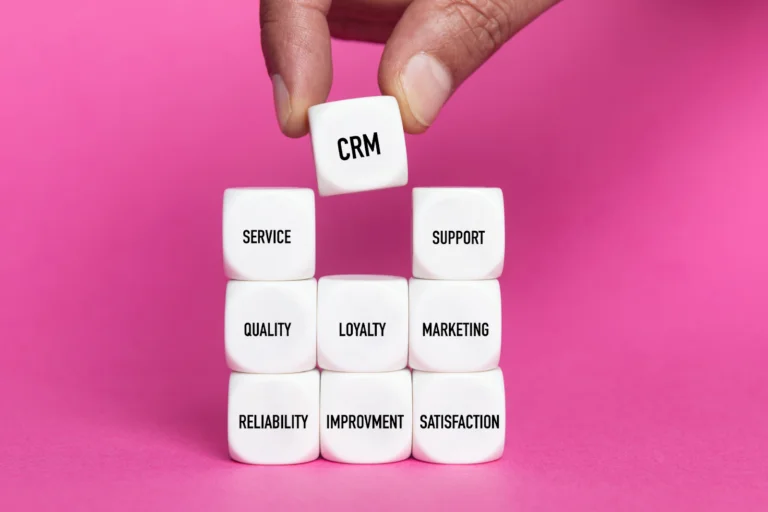 White dice with words like CRM, SERVICE, and SUPPORT stacked in front of a pink background